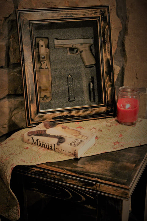 A 11x17 dark wood gun concealment picture frame with a handgun, magazine, and knife behind its glass. 