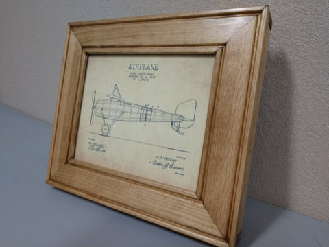 An 8x10 golden oak gun concealment picture frame with a diagram of a single-propeller airplane inside. 