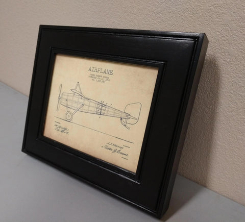 An 8x10 gun concealment picture frame finished in black with a diagram of a single propeller airplane inside. 