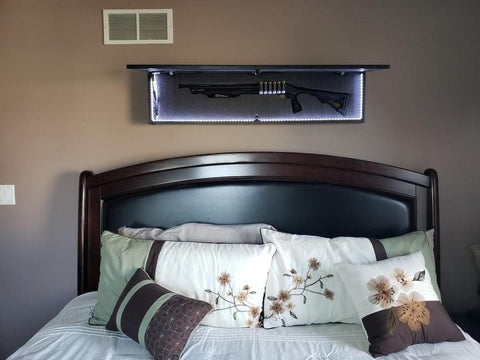 Door of gun concealment wall art hanging over bed opened to show shotgun in foam insert.