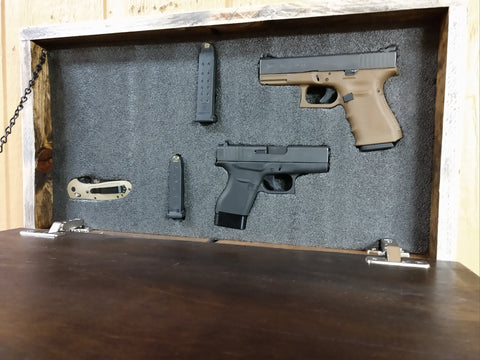 Interior of dark brown gun concealment wall decor with handguns, ammunition pouches, and knife in thick foam insert.