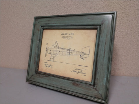 An 8x10 distressed teal gun concealment picture frame with a diagram of a single propeller airplane inside. 
