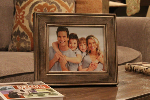 An 8x10 gun concealment picture frame, with a picture of a family of four inside, sitting on a coffee table. 