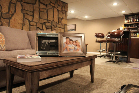 An 11x14 gun concealment picture frame sitting on a coffee table with its hidden compartment open to reveal a handgun.