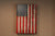 A wooden American flag gun concealment case hanging vertically on a brown wall.