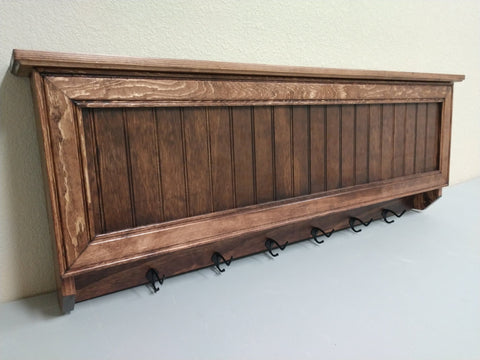 A gun concealment coat rack, made from Oak and finished with a red wood stain. 
