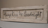 White, distressed concealment wall art with black lettering "Always Kiss Me Goodnight" leaning against wall.