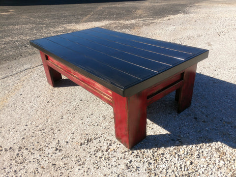 A sliding top gun concealment coffee table with a black painted top and red legs.