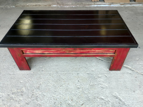 A sliding top gun concealment coffee table with a black painted top and red legs.