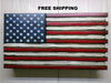 Weathered wood concealment flag painted with US flag where the red stripes extend a little bit further than the white stripes with the words "Free Shipping" above.