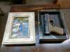 A 5x7 distressed white gun concealment picture frame, separated into two pieces, including its hidden compartment with a handgun inside.