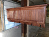 A wooden gun concealment coat rack with six metal hooks, finished with a cherry stain, hanging on a wooden post. 