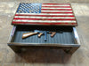 A gun concealment coffee table with it's American flag sliding top open to reveal a rifle.