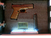 The hidden compartment inside of a concealment flag, lit with LED lights, open to reveal a handgun, American flag patch and a magazine.