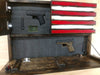 Opened American Flag gun concealment case with small compartment in top left holding a pistol and large compartment on bottom holding a pistol