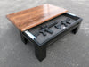 A black gun concealment coffee table with it's sliding top open to reveal two rifles.