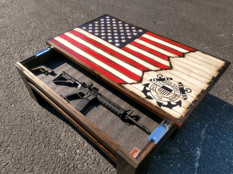 A gun concealment coffee table with an American flag sliding top with a US Coast Guard logo painted on it, opened to reveal a rifle.