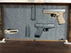 Inside of mini gun storage wall decor holding handguns, ammunition, and a knife in the foam interior.