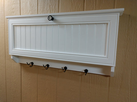 A medium-sized wooden gun concealment coat rack, with four black metal hooks, painted white. 