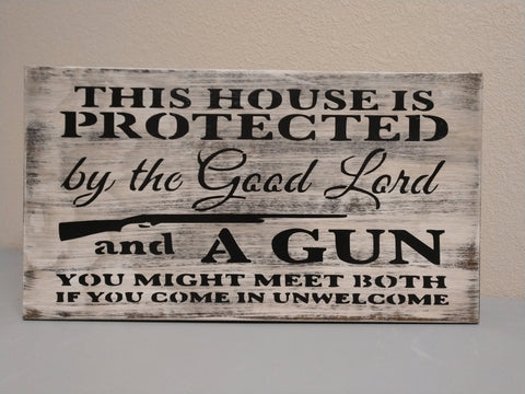 White, distressed, mini gun storage wall decor with saying "This house is protected by the Good Lord and a gun."