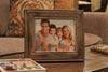 An 11x14 gun concealment picture frame, with a picture of a family of four inside, sitting on a coffee table. 