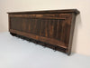 A gun concealment coat rack finished with a dark brown wood stain. 
