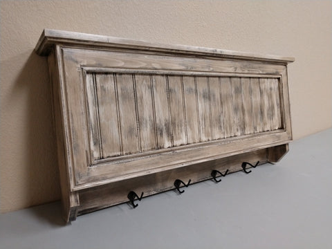 A medium-sized gun concealment coat rack, made from distressed wood, with four black metal hooks. 